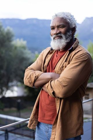 Senior african-american man leaning on balcony railing overlooking mountain valley