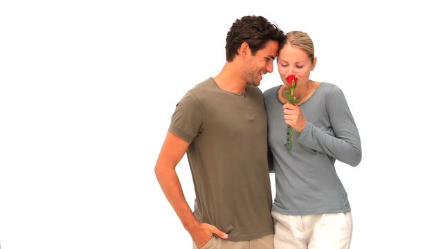 Man showing affection by gifting red rose to woman, both smiling warmly. Perfect for illustrating themes of romance, gifts on special occasions like anniversaries or Valentine's Day, and expressions of love and care in promotional materials or greeting cards.