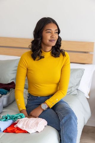 Young woman organizing clothes for trip at home