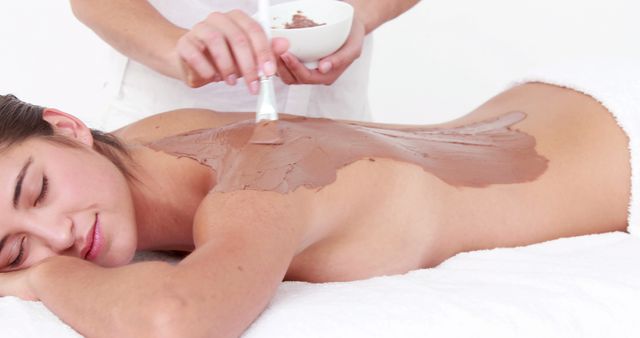 A young Caucasian woman enjoys a relaxing chocolate spa treatment, with copy space. Spa therapies like this are often sought for their potential benefits to skin health and stress relief.