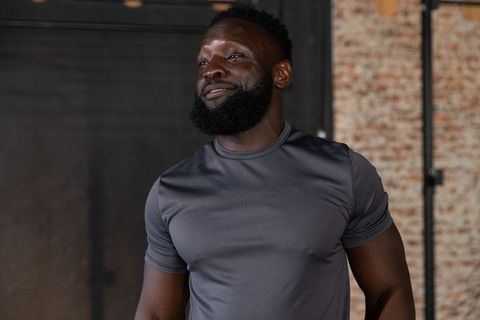 African american man standing and looking left in warehouse wearing fitted athletic tee