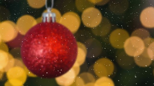 Capturing the festive essence of Christmas, this video showcases a vibrant red ornament hanging in front of blurred bokeh lights, with snow gently falling. Ideal for holiday cards, festive promotions, seasonal newsletters, blog posts, and social media content celebrating Christmas and winter themes.