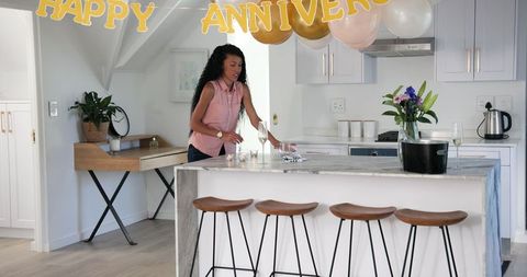 Woman Tidying Up Kitchen After Anniversary Celebration