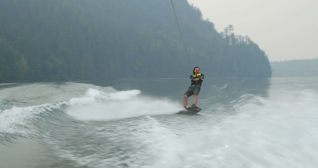 Man wakeboarding on calm lake surrounded by forest - Download Free Stock Images Pikwizard.com