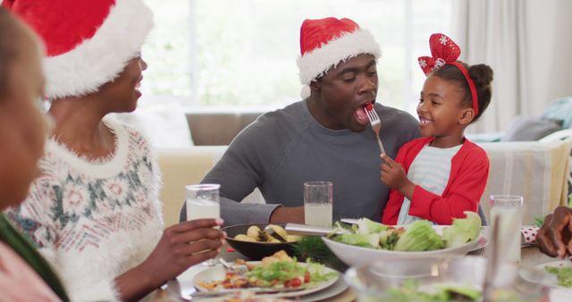 Christmas scene with family joyfully sharing meal, playful interaction between father and daughter. Great for holiday greeting cards, family-oriented advertising, articles about family bonding during holidays.