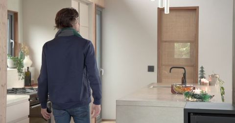 Man Standing in Modern Cozy Kitchen with Winter Candles and Decorations