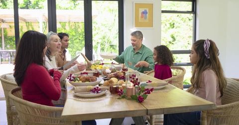 Multigenerational family gathered for festive holiday feast at sunlit wooden dining table
