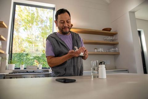 Mature asian man preparing daily medication in modern minimalist kitchen wellness routine
