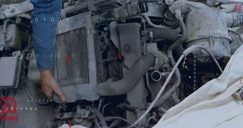 Mechanic removing radiator from dusty engine bay with digital binary overlay