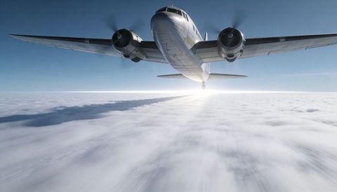 Vintage twin-engine airplane flying above cloud deck with sunlit horizon and shadow