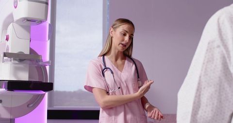 Nurse technologist explaining mammogram procedure to patient in radiology room