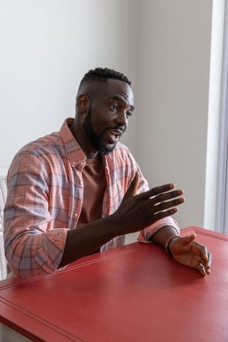 Mid Adult African American Man Gesture While Talking at Red Table