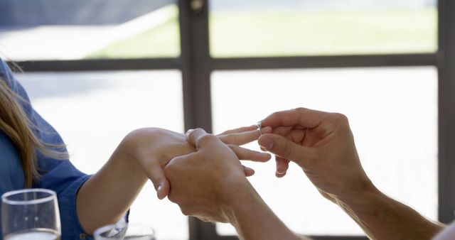 Man Placing Engagement Ring on Woman's Finger Inside Café - Download Free Stock Images Pikwizard.com