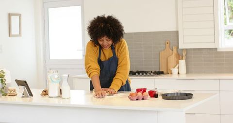 African American woman kneading dough on bright modern kitchen island for home baking