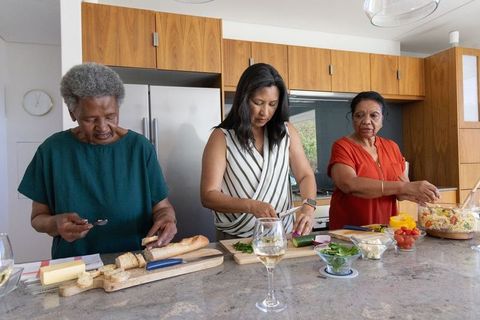 Multigenerational african american women preparing meal together at modern kitchen island