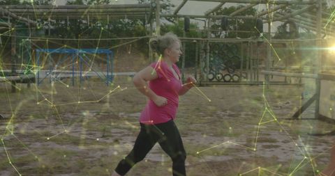 Woman running through an outdoor obstacle course with digital effects enhancing action. This can be used for promoting fitness apps, outdoor exercise programs, or demonstrating a merging of fitness and technology in inspirational campaigns.