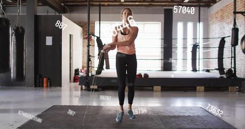 Fit woman skipping rope inside industrial boxing gym for high-intensity cardio workout