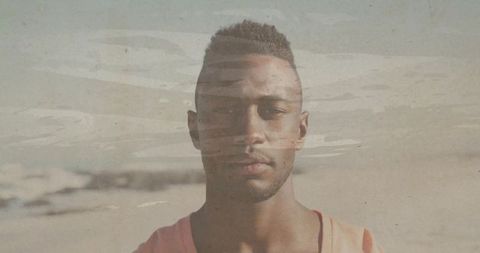 Contemplative young man on muted beach with vintage film overlay capturing solitude