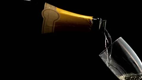 Champagne Pouring Into Glass Against Black Background in Slow Motion