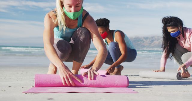 Group of Women Wearing Face Masks Rolling Yoga Mats on Beach - Download Free Stock Images Pikwizard.com