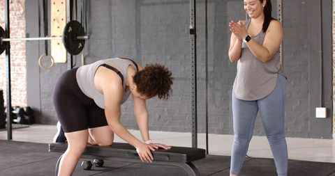 Women training together in gym spotting each other, bench bracing and encouraging workout