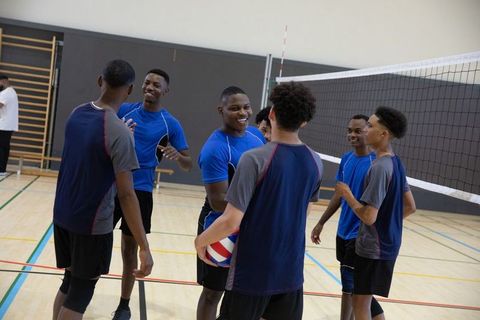 African american teen male volleyball team celebrating on indoor gym court