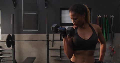 Woman exercising with dumbbell in modern gym