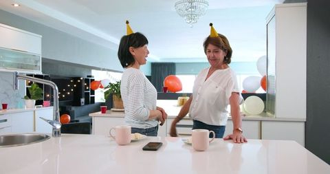 Senior Friends Clean Up After Joyful Birthday Party in Kitchen