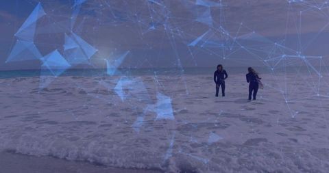 Couple walking through surf with futuristic blue digital network overlay on overcast beach shore