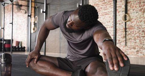 Man Practicing Elastic Hamstring Stretch in Urban Fitness Gym