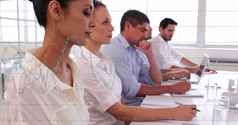 Business professionals are working together in an office environment, overlaid with financial data graphics suggesting data analysis. Ideal for visuals highlighting corporate strategy, financial development, economic data processing, and collaborative teamwork.