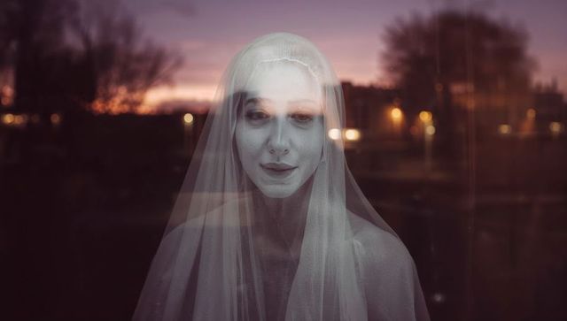 Ethereal woman with veil reflected at dusk