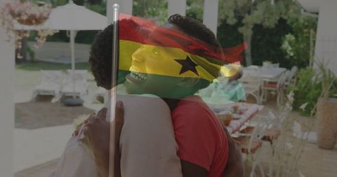 Joyful hug under ghana flag on sunlit patio