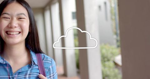 Smiling teen wearing blue shirt and backpack on sunlit campus walkway with cloud icon