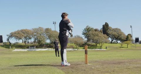 Cricket Players Preparing for Bowl on Sunny Field
