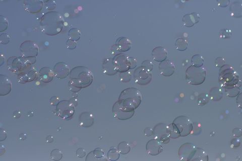 Floating iridescent bubbles against clear blue sky