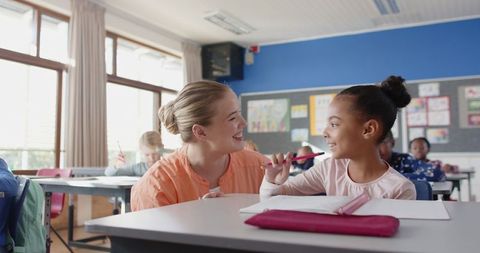 Mentor guiding young student in classroom interaction
