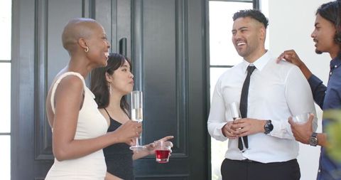 Diverse group networking and holding champagne flutes in foyer at semi-formal gathering