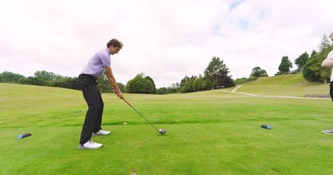 Friends enjoying tee off on scenic golf course