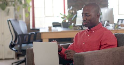 Confident Businessman Using Laptop in Modern Office Workspace