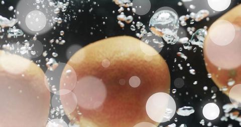 Stone fruit floating with sparkling water bubbles and soft bokeh close-up