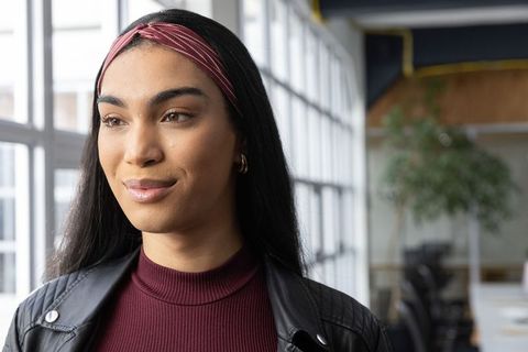 Young professional woman in burgundy top and pink headband looking in co-working space