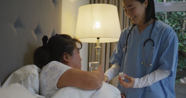 Smiling asian female doctor helping female patient in bed take her medication. medicine, health and healthcare services.