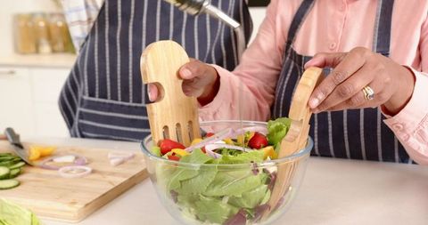 Friends Tossing Fresh Salad in Modern Kitchen Setting