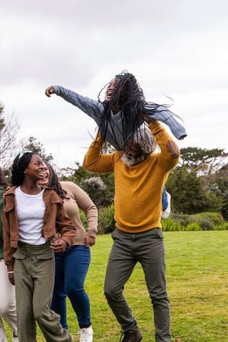 African american multigenerational family enjoying playful park moment, senior lifting teen