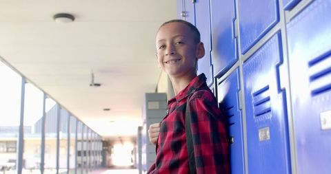 Smiling Young Student Leaning on Blue School Lockers