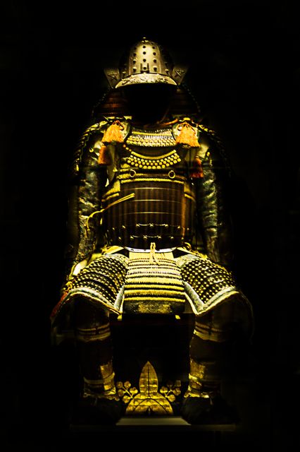 Traditional samurai armor on dark background, showing intricate design and craftsmanship. Suitable for use in historical documentaries, educational materials, and cultural articles.