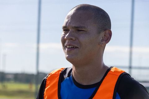 Male athlete training outdoors with orange bib on blue shirt