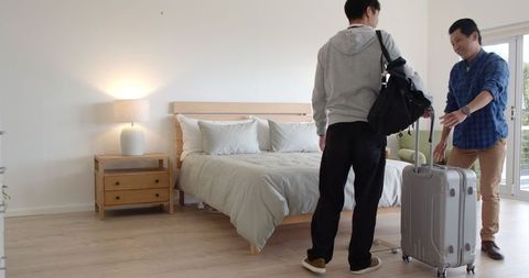 Father and son arriving in modern bedroom with luggage
