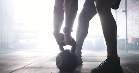 Male athlete lifting kettlebell in gym training session